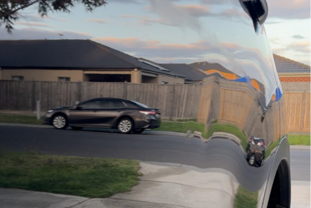 Mirror-like reflection of a car on its shiny paint surface after a thorough decontamination process.