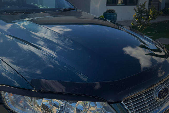 Close-up of a Ford car’s glossy paint finish after professional paint correction, showcasing a mirror-like shine.
